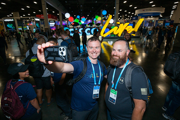 Two attendees taking a selfie in front of the Cisco Live letters
